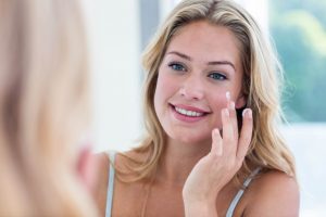 Smiling pretty woman applying cream on her face in bathroom, Image: 280469861, License: Royalty-free, Restrictions: , Model Release: yes, Credit line: Profimedia, Wavebreak
